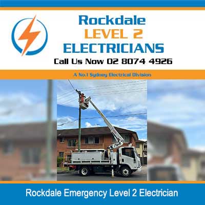 Emergency electrician working above utility truck with extended boom lift near power lines and residential building in Rockdale